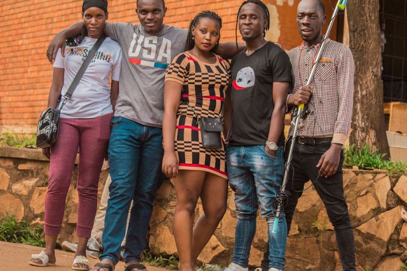 A group of adults in casual clothes standing together outdoors in daylight.